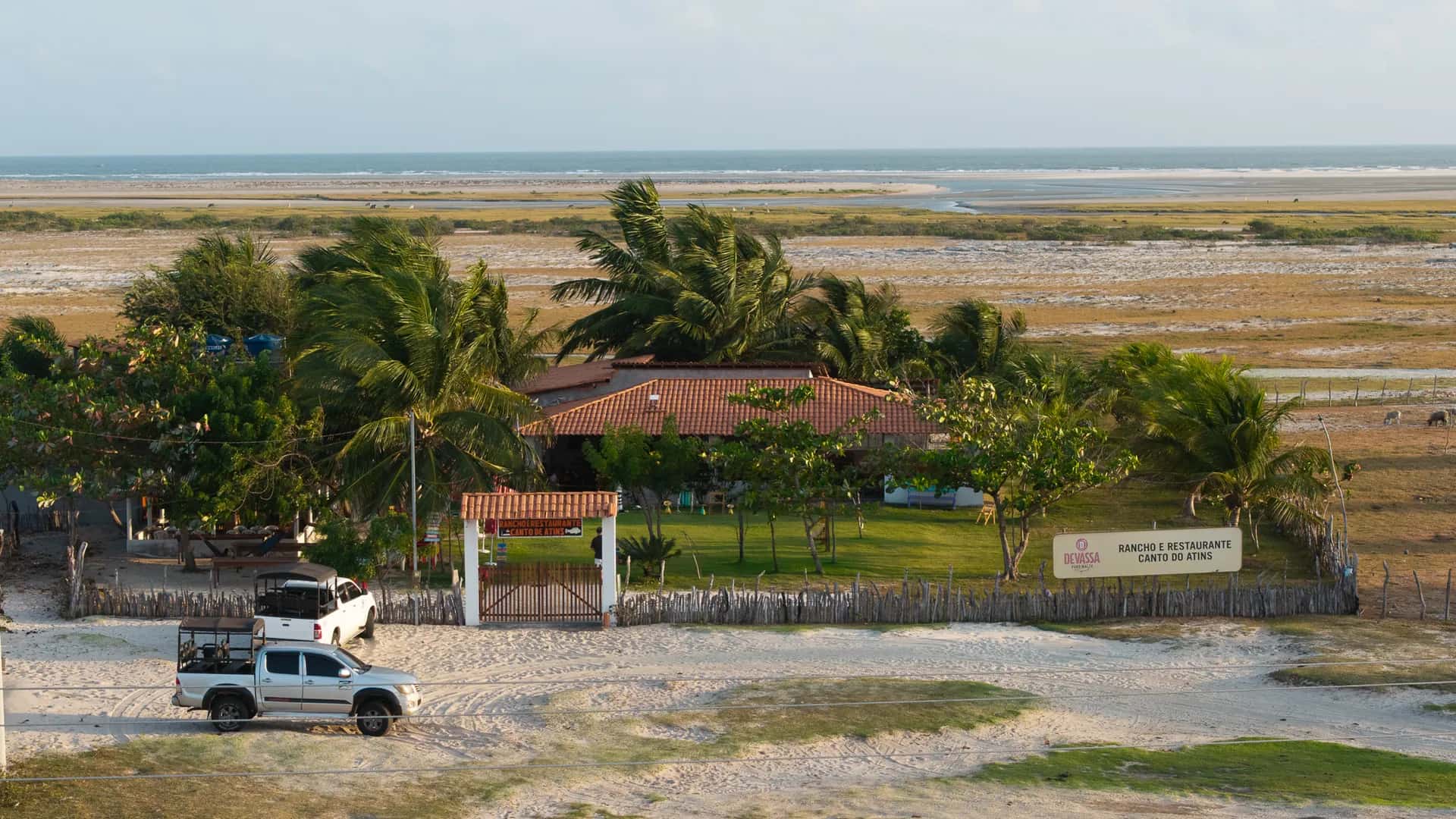 Rancho e Restaurante Canto de Atins visto do alto: telhado de barro entre coqueiros, com a praia e o mar ao fundo